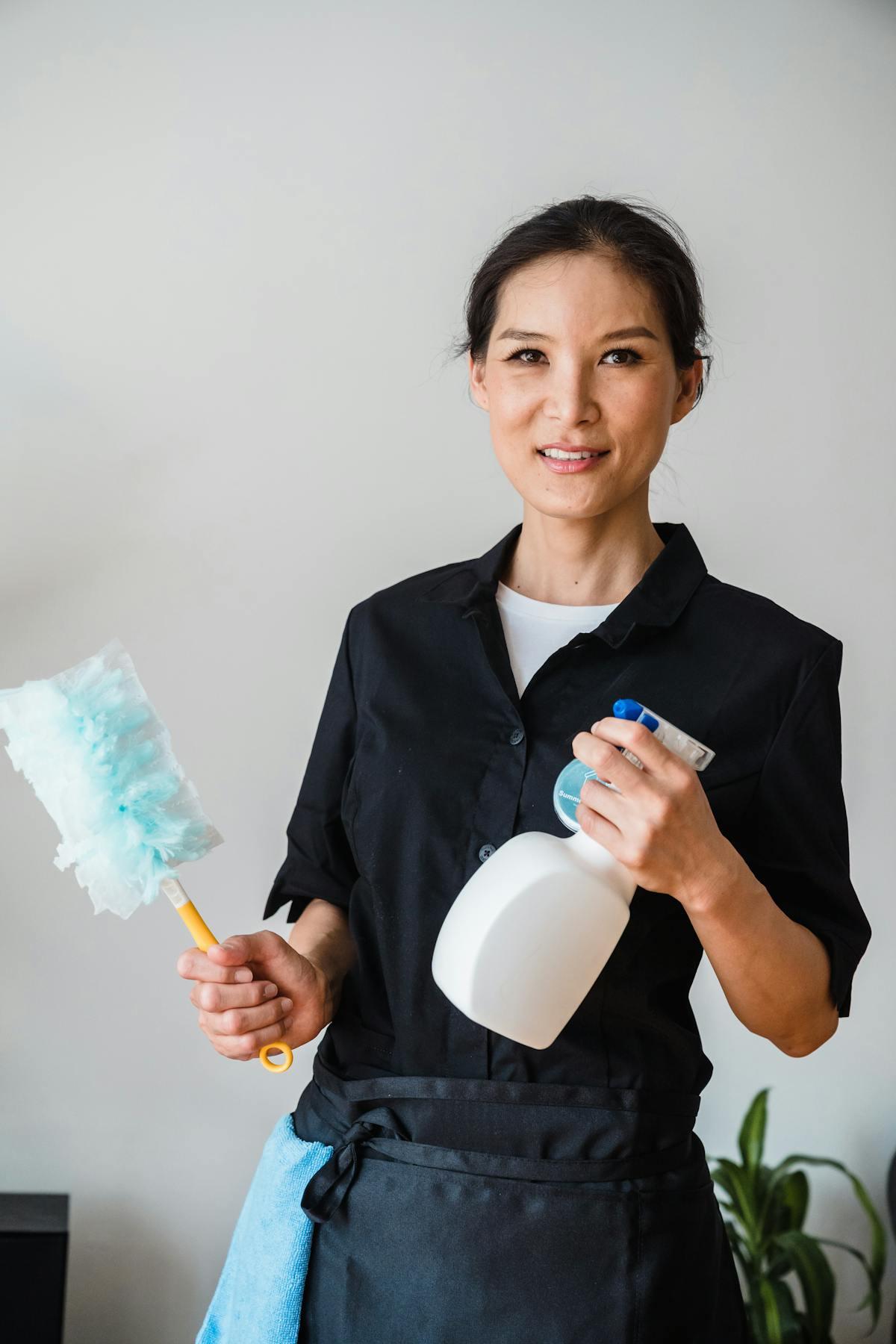 Housekeeper holding cleaning tools in a household setting.