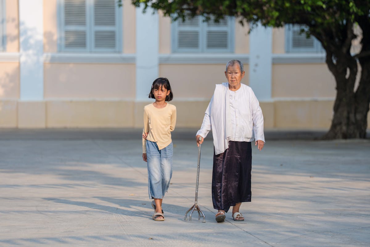 A caretaker walking with an elderly Asian woman in a Singapore garden