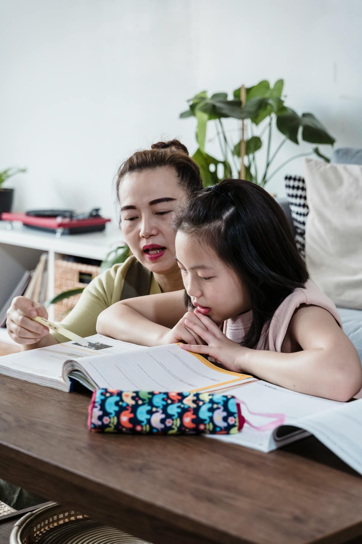 A caretaker helping a young child with homework at a Singapore kitchen table
