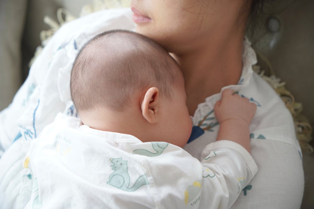 A caregiver gently holding a sleeping newborn baby
