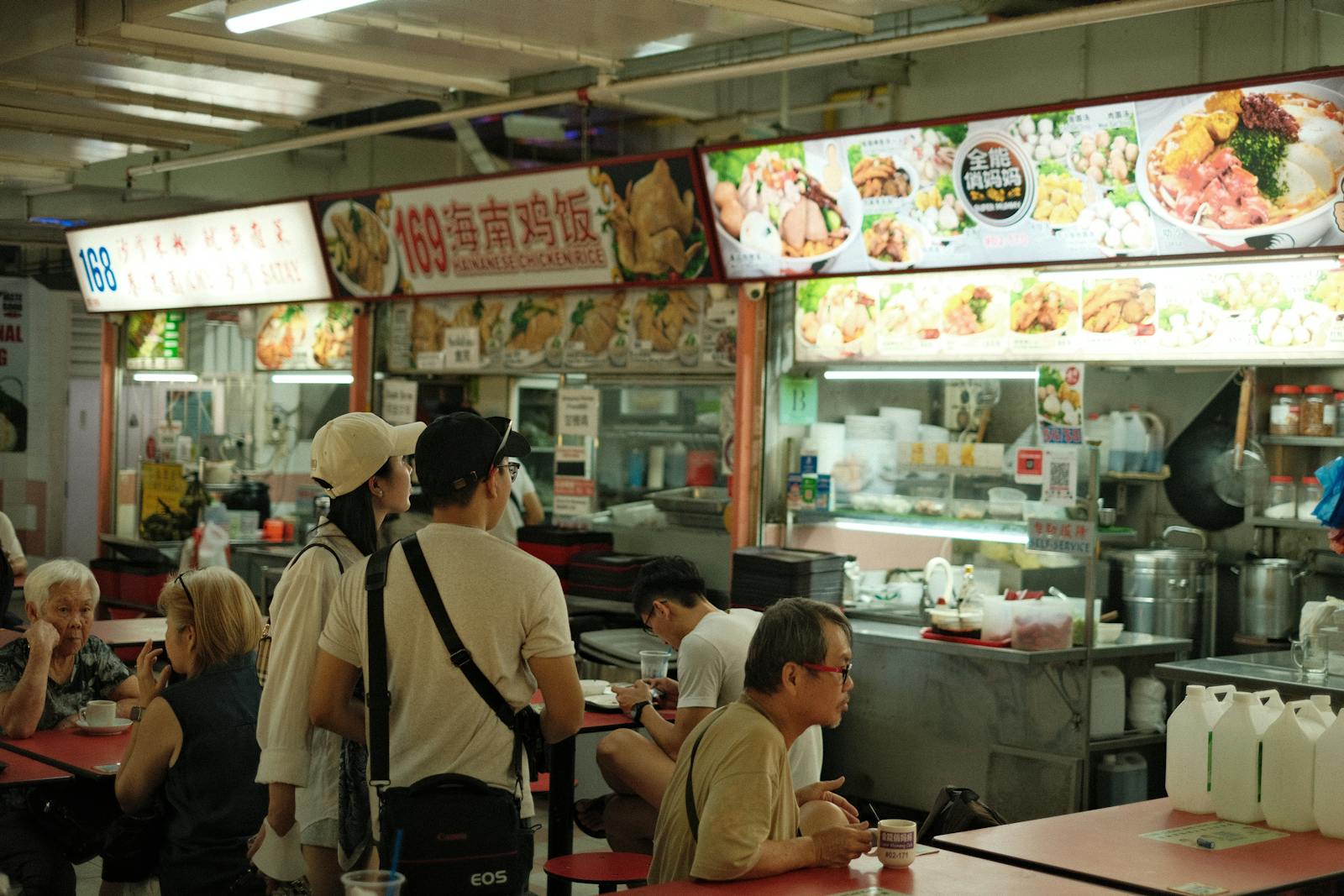 Inside a Singapore hawker centre, with a Hainanese chicken rice stall in the background